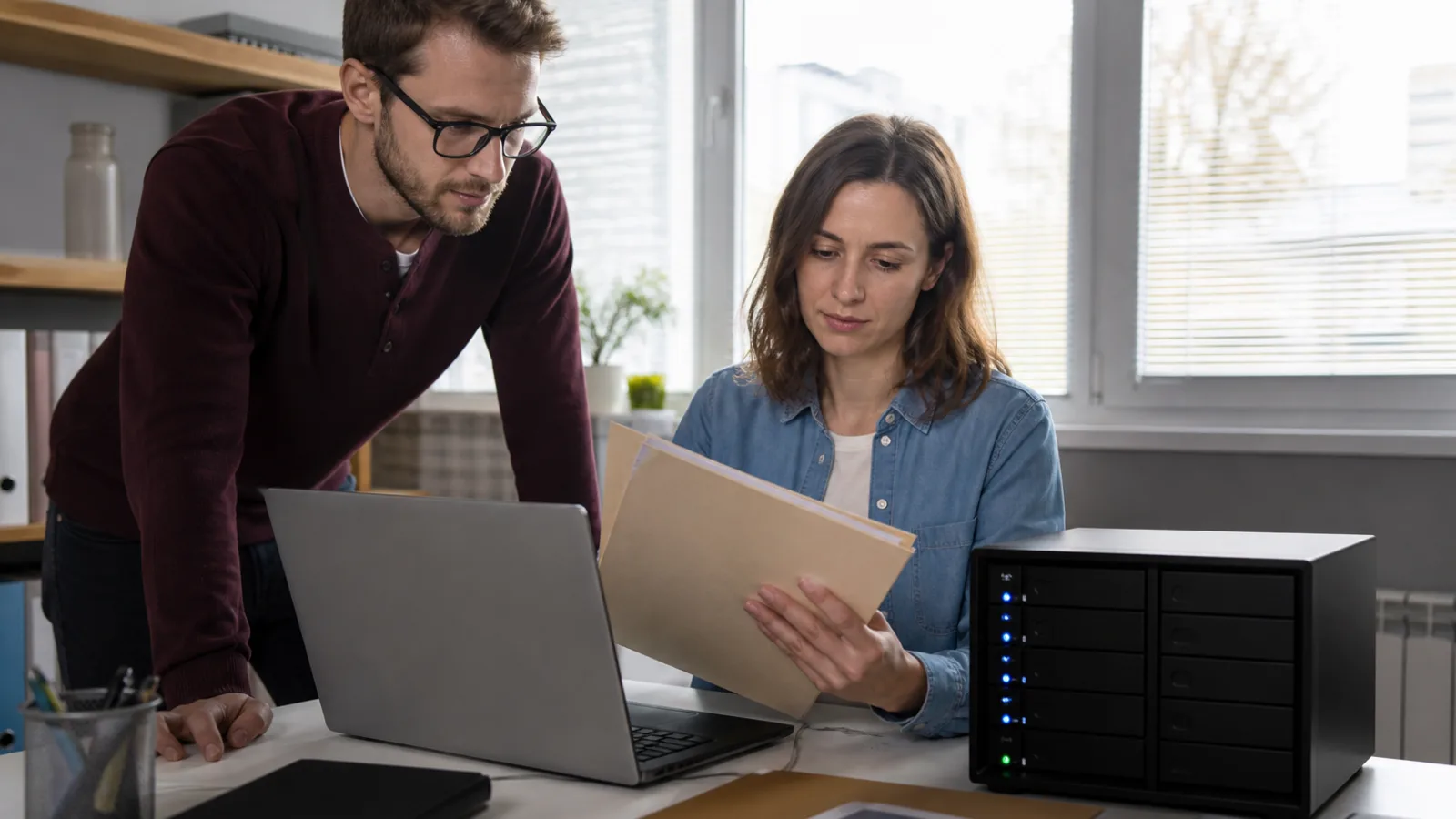Two people sharing files around a laptop and network drive